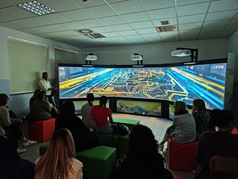 Sala didattica immersiva con proiettori e studenti durante una sessione educativa